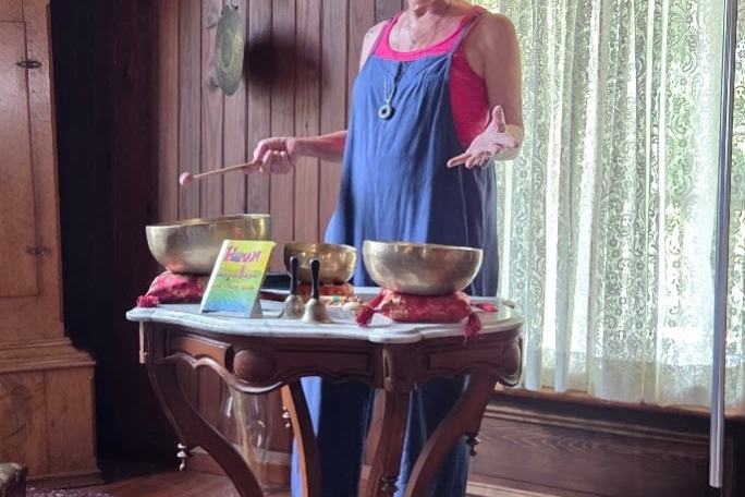 Woman playing singing bowls on a small table indoors.
