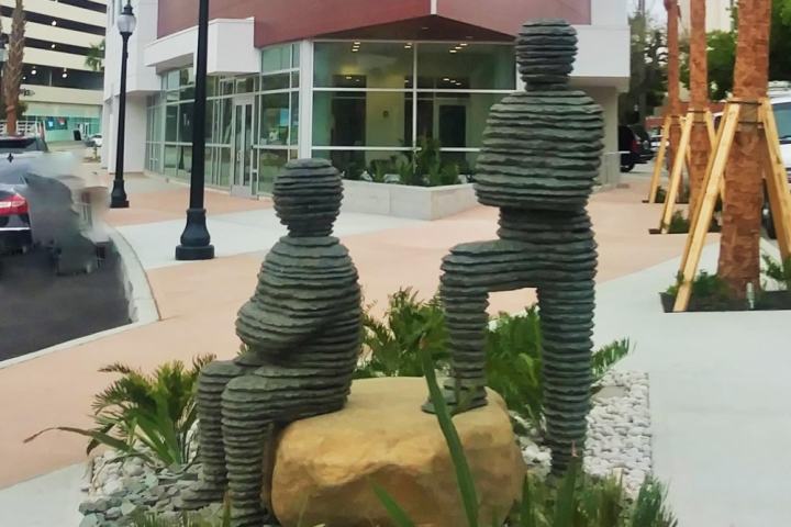 Abstract stone sculptures of two human figures outside a modern building.