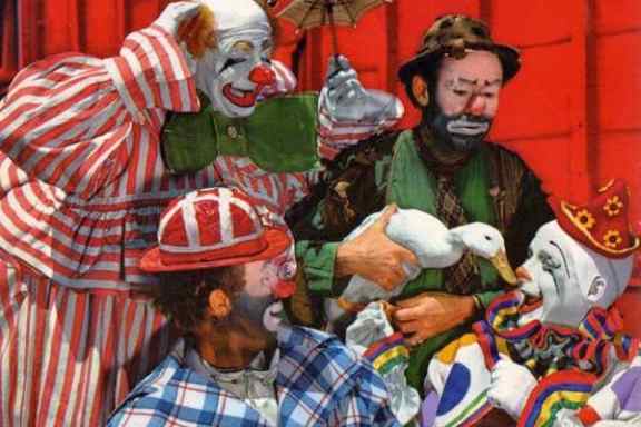 Four clowns with face paint and colorful costumes interacting with a duck against a red backdrop.