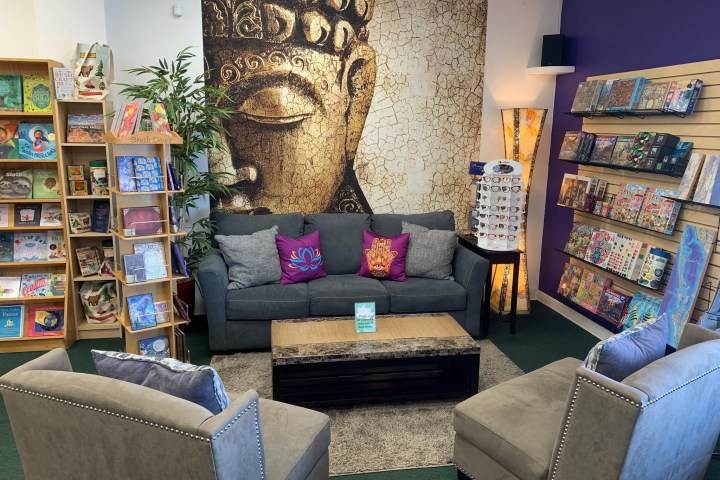 Cozy bookstore corner with Buddha mural, gray sofa, and colorful shelves.