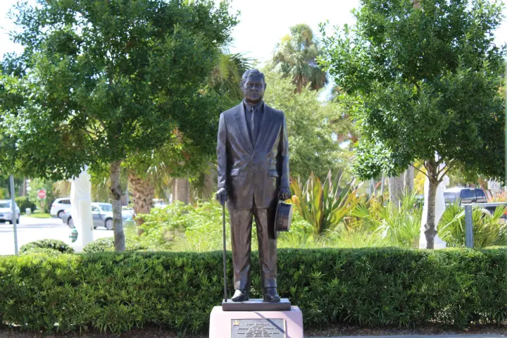 a statue of a man standing in front of a tree