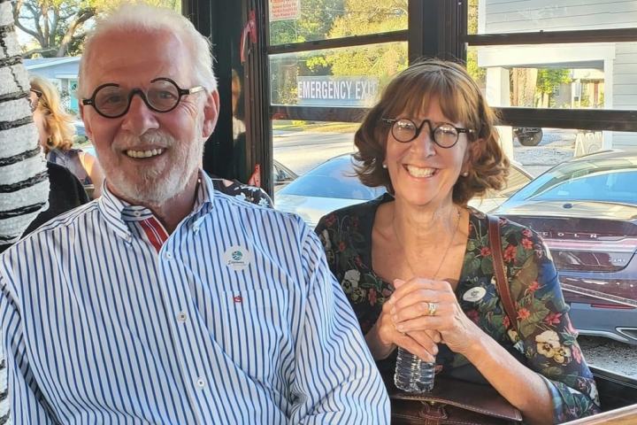 Two people smiling, sitting inside a trolley with wooden seats.