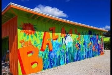 Colorful building mural with 'The Bazaar' and underwater theme under a blue sky.