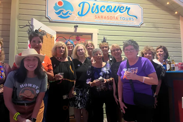 Group of women in costumes posing outside Discover Sarasota Tours building.