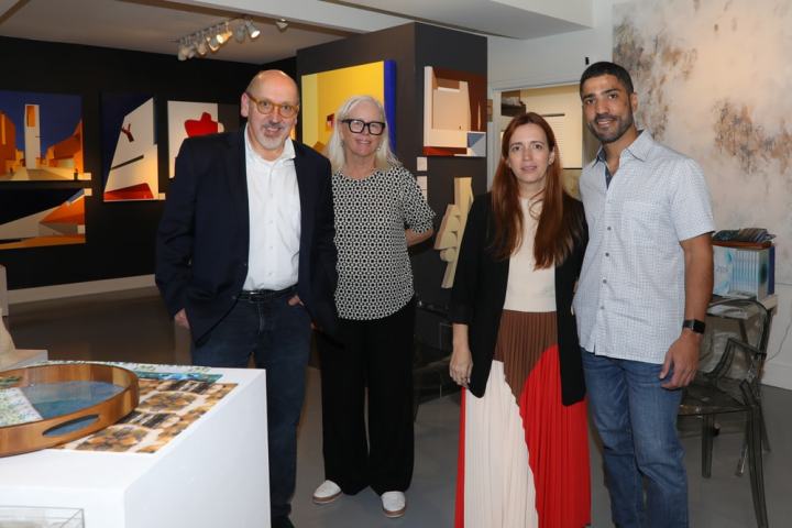 Four people standing together in an art gallery with modern paintings on the walls.