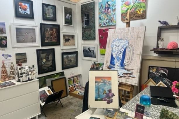 Art studio with framed paintings, a table of prints, and colorful wall decor.