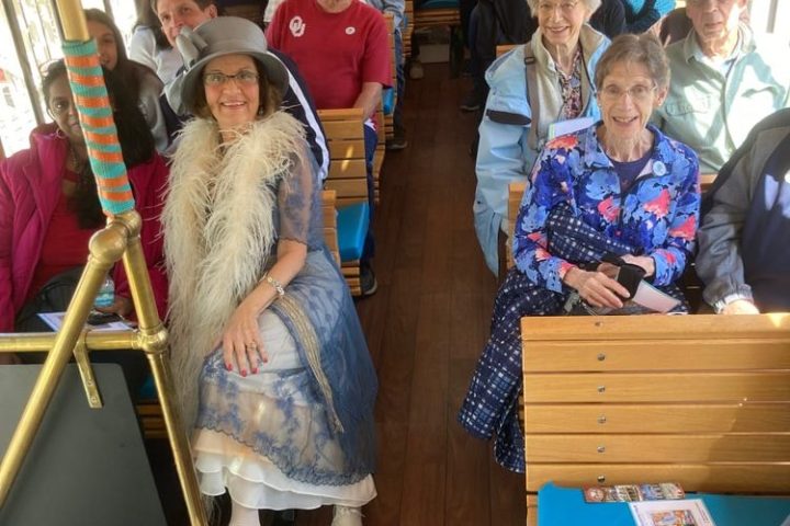 Group of people seated inside a vintage-style tram with wooden interior.