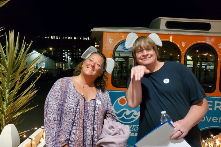 a man and a woman standing in front of a bus