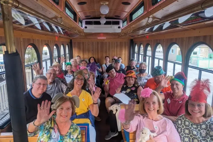 Group of people smiling and waving inside a trolley.