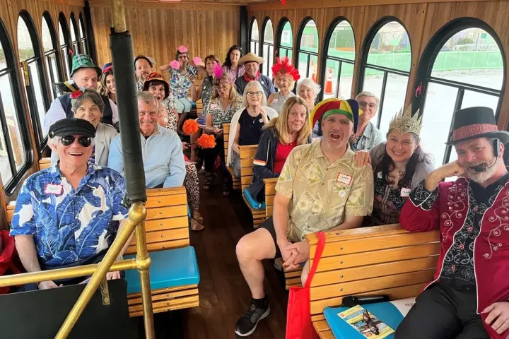 Group of people in colorful hats smiling inside a trolley.