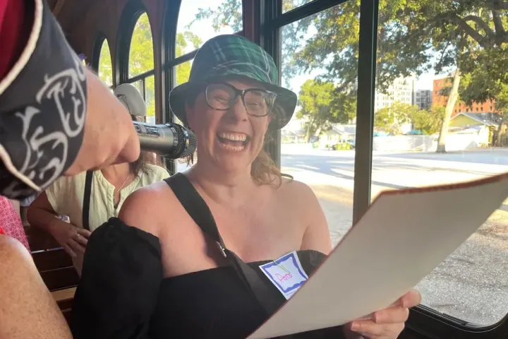 Laughing woman in a hat holding paper inside a trolley.