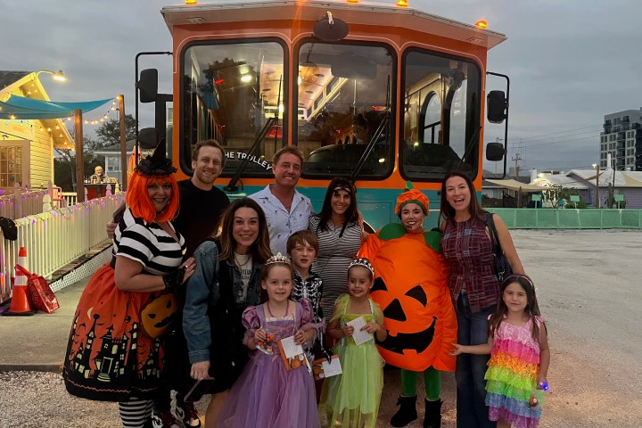 Group in Halloween costumes posing in front of a trolley at dusk.