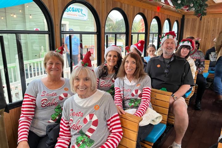 Group of people in festive attire on a decorated tour bus for a holiday event.