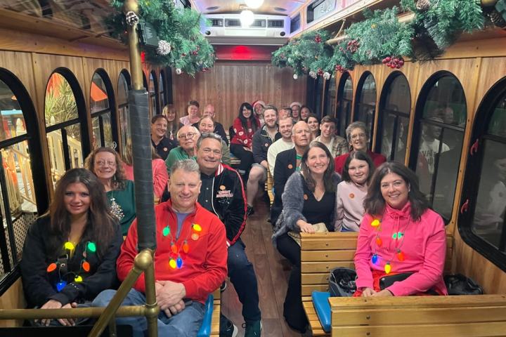 A group of people seated inside a festively decorated bus with Christmas garlands.