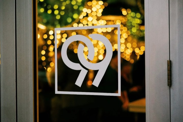 Glass door with '99' logo and bokeh lights visible through it.