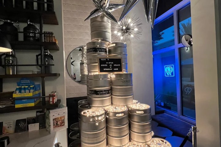 Stacked beer kegs with lights, silver star decorations, and a mirror in a bar corner.