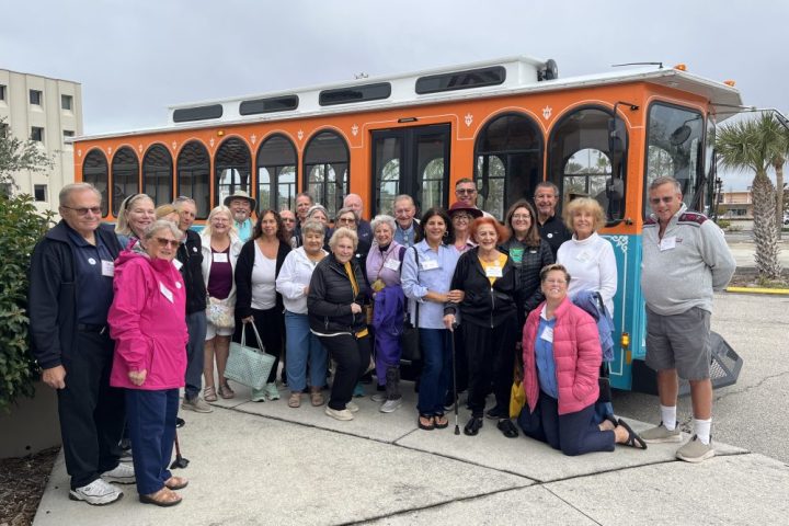 A group of people standing in front of the trolley posing for the camera for Venice City Sightseeing Tour!