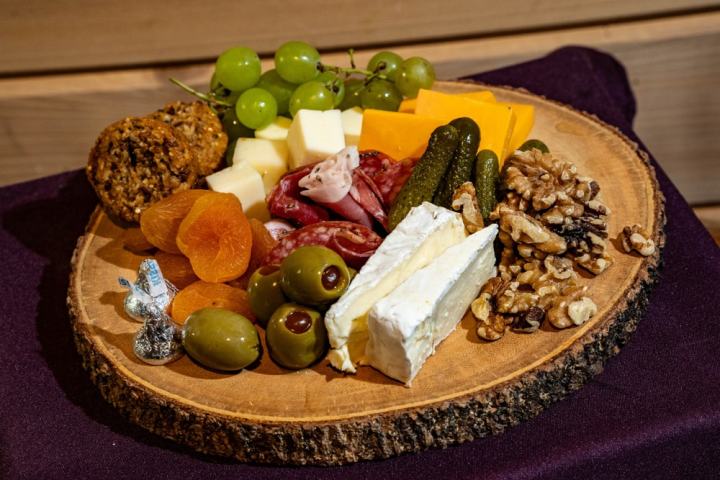 Charcuterie board with cheese, meats, olives, nuts, and fruits on a wooden slab.