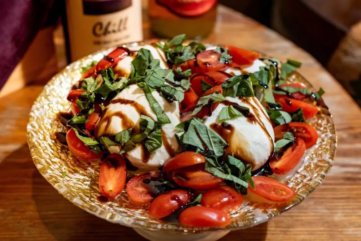 Caprese salad with mozzarella, cherry tomatoes, basil, and balsamic glaze on a glass plate.