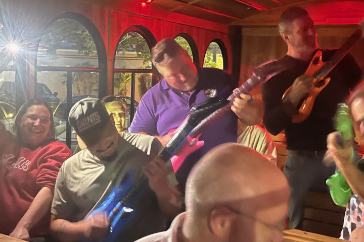 a group of people on the trolley playing with inflatable guitars on singalong trolley