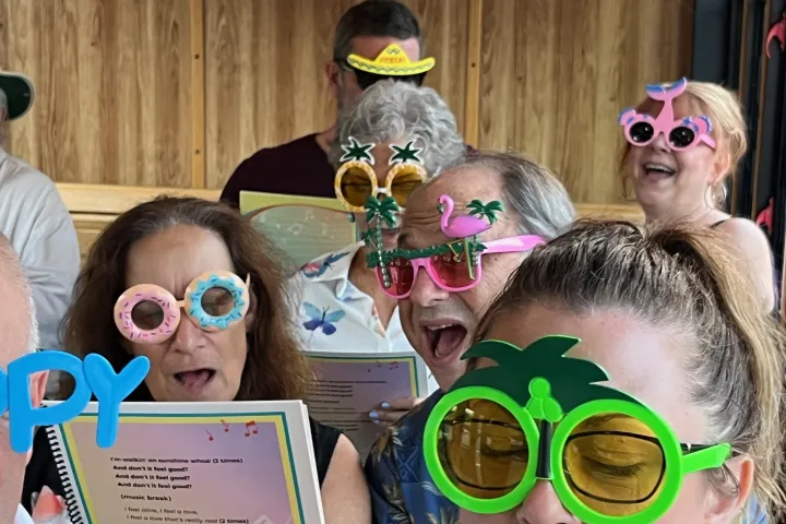 a group of people wearing sunglasses on the trolley and singing along