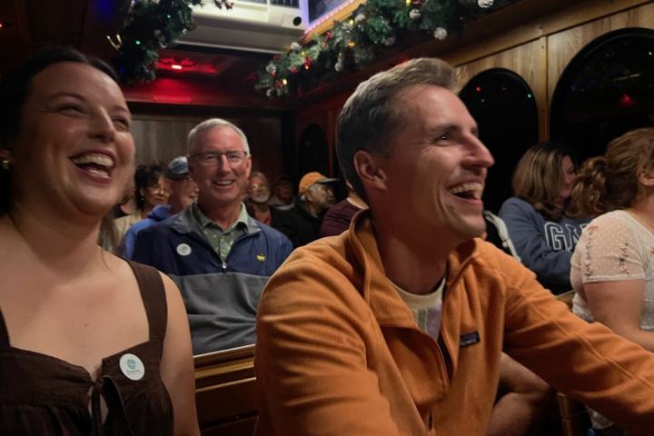 People smiling and laughing inside a decorated bus with festive greenery.