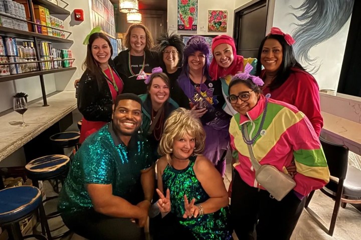 Group of people in colorful costumes posing indoors, smiling.