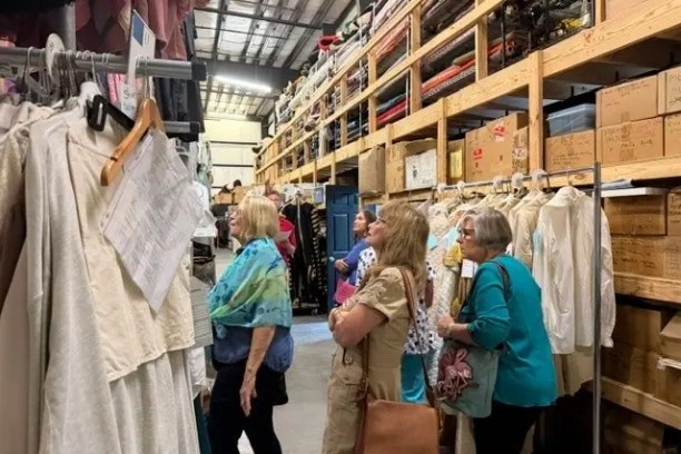 Women browsing garments in a clothing warehouse.