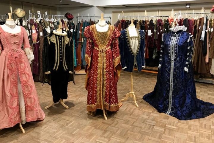 Four mannequins display historical costumes in a vintage clothing shop.
