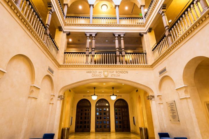 Elegant atrium with arches, balconies, and warm lighting in a pale yellow color.