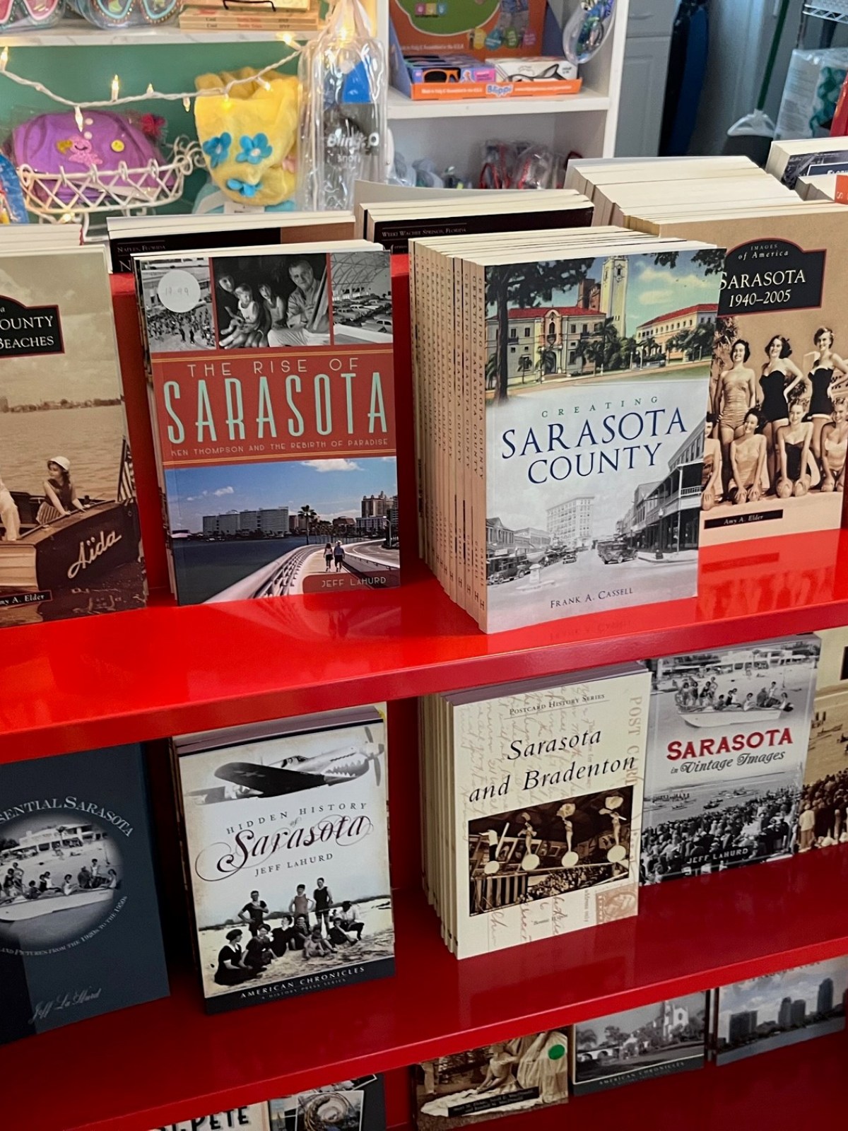 Red bookshelf with Sarasota-themed books on display.