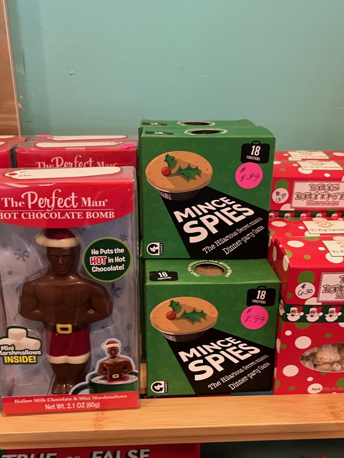Display of hot chocolate bombs, mince pies, and boxed treats on a shelf.