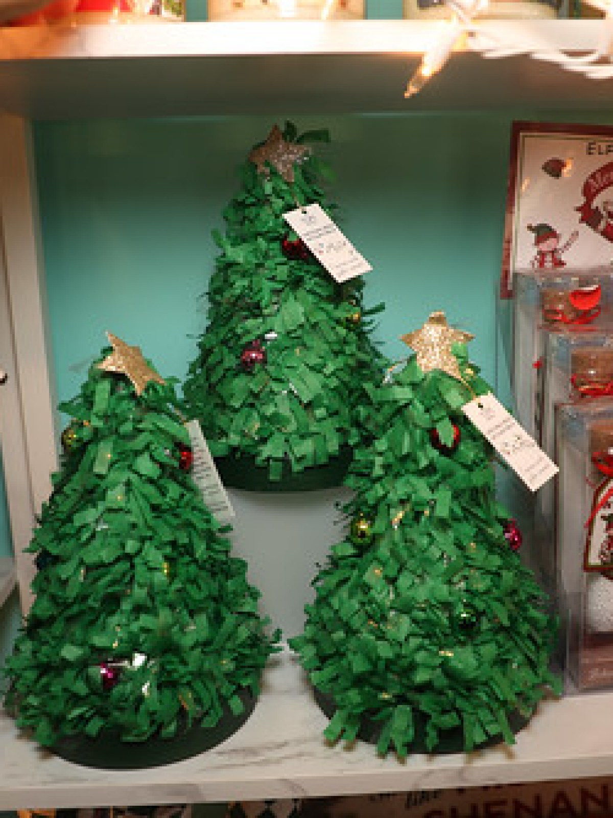 Shelf with mini green Christmas trees and holiday-themed treats.