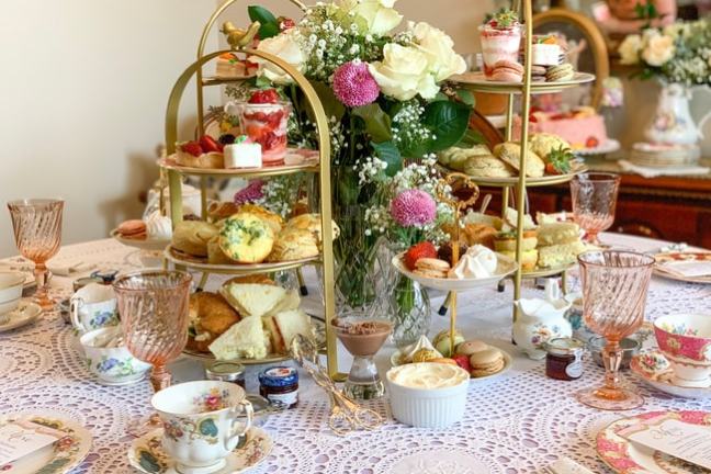 Elegant afternoon tea setup with tiered trays of pastries and floral centerpiece.