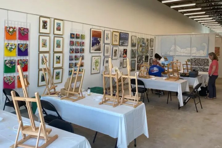 Art studio with easels, wall art, and people preparing for a class.