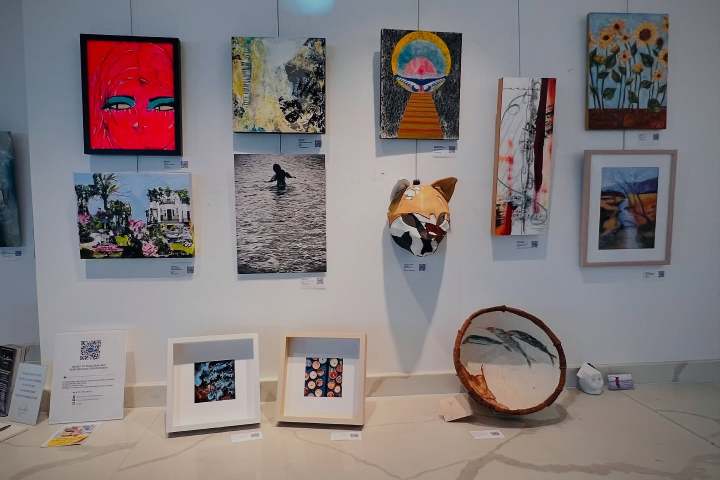 Colorful paintings and art pieces displayed on a wall and table.