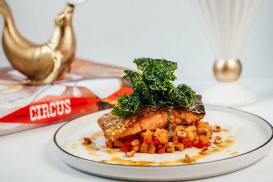 Plated gourmet salmon dish with vegetables and greens.