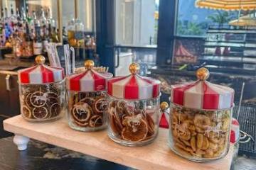 Four decorative jars with circus tent lids on a tray at a bar.
