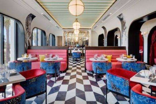Elegant restaurant interior with red booths, blue chairs, and checkered floor.