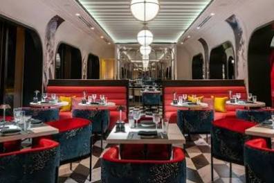 Elegant restaurant with red and blue seating, black and white floor, and hanging globe lights.