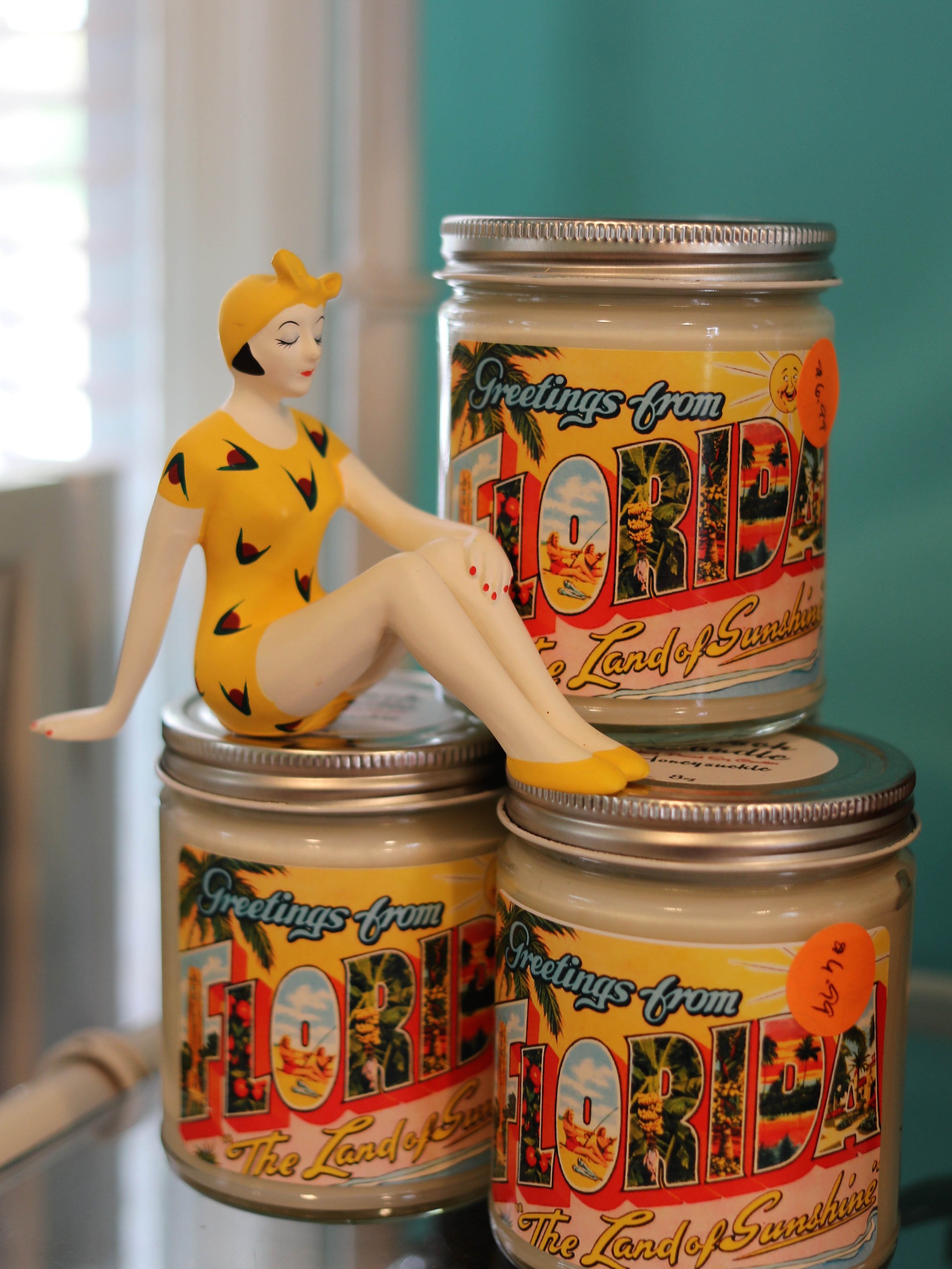 Three Florida-themed jars with a retro figure in a yellow swimsuit perched on top.