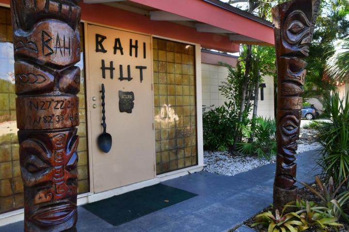 Entrance with tiki carvings and 'RAHI HUT' sign on door