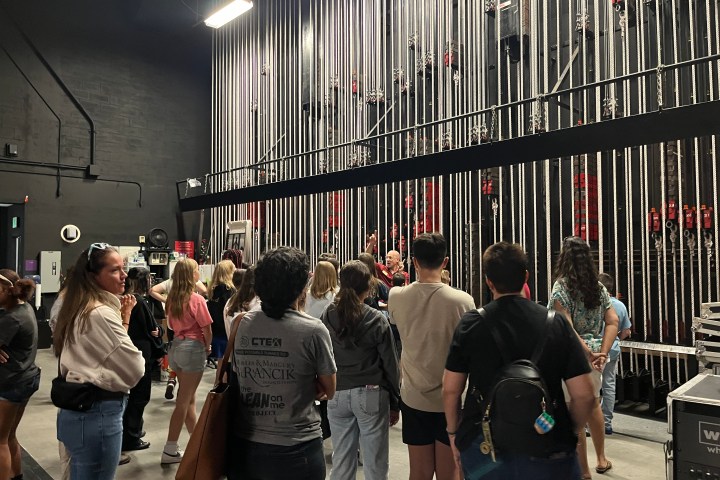 Group of people touring a theater backstage area with rigging systems.