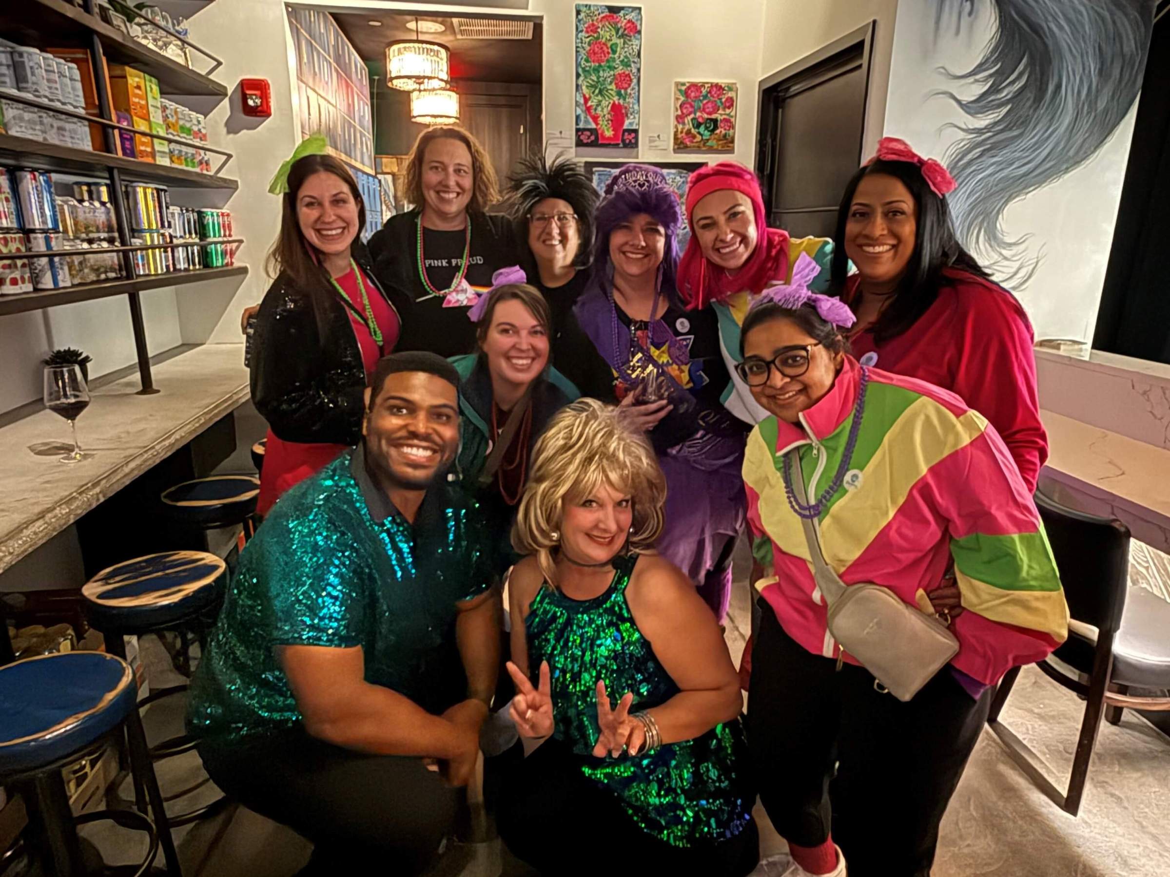 Group of people in colorful costumes posing indoors, smiling.