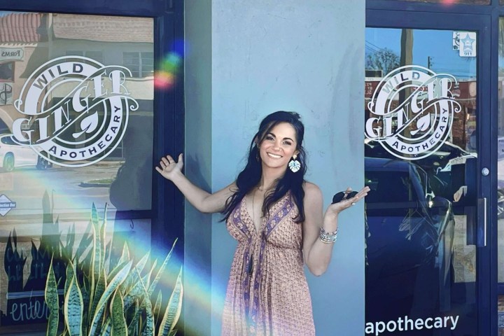 Smiling woman posing in front of Wild Ginger Apothecary store.