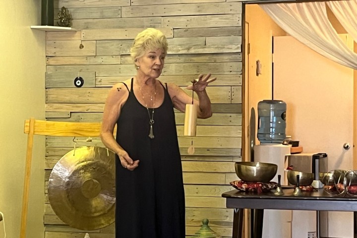 Woman holding a chime in a room with a gong and singing bowls.