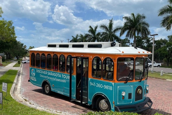 Tour trolley parked on a sunny street with palm trees in the background.